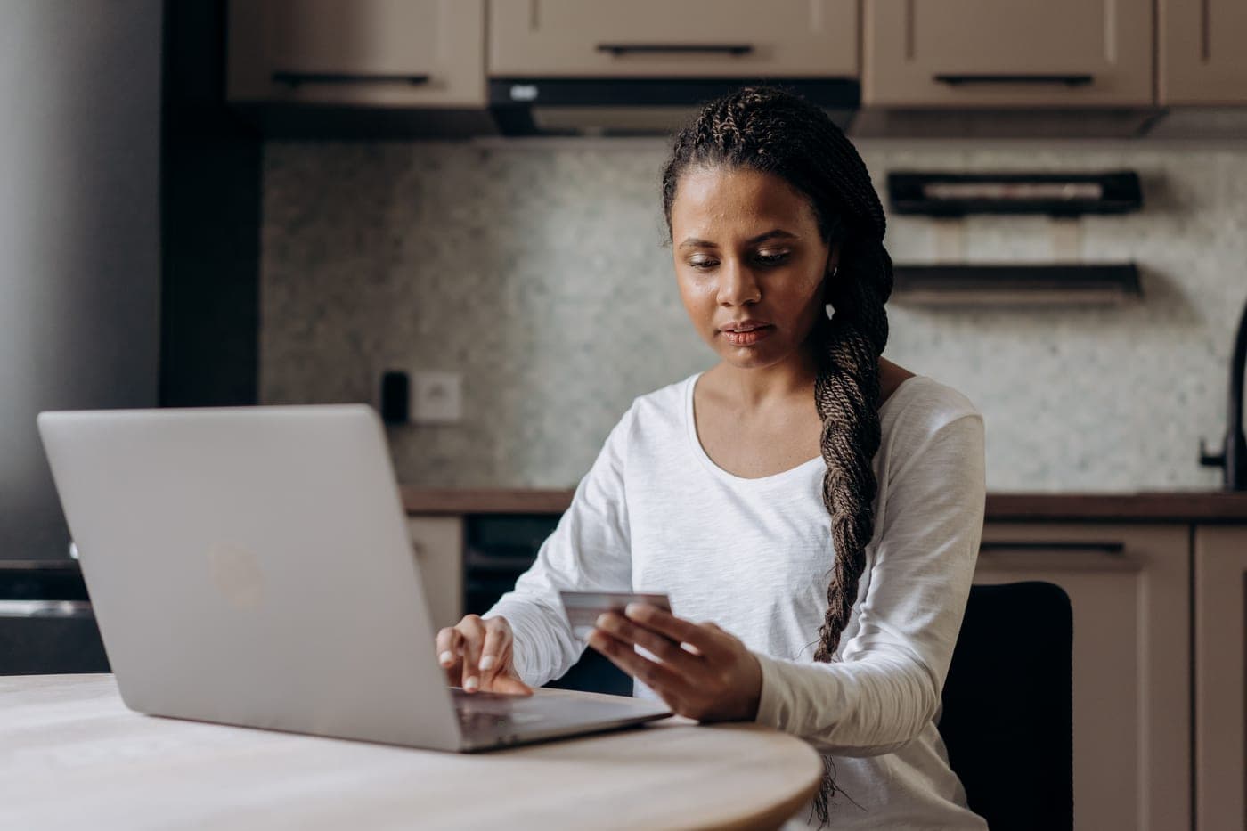 A person shopping online at a kitchen table with a laptop